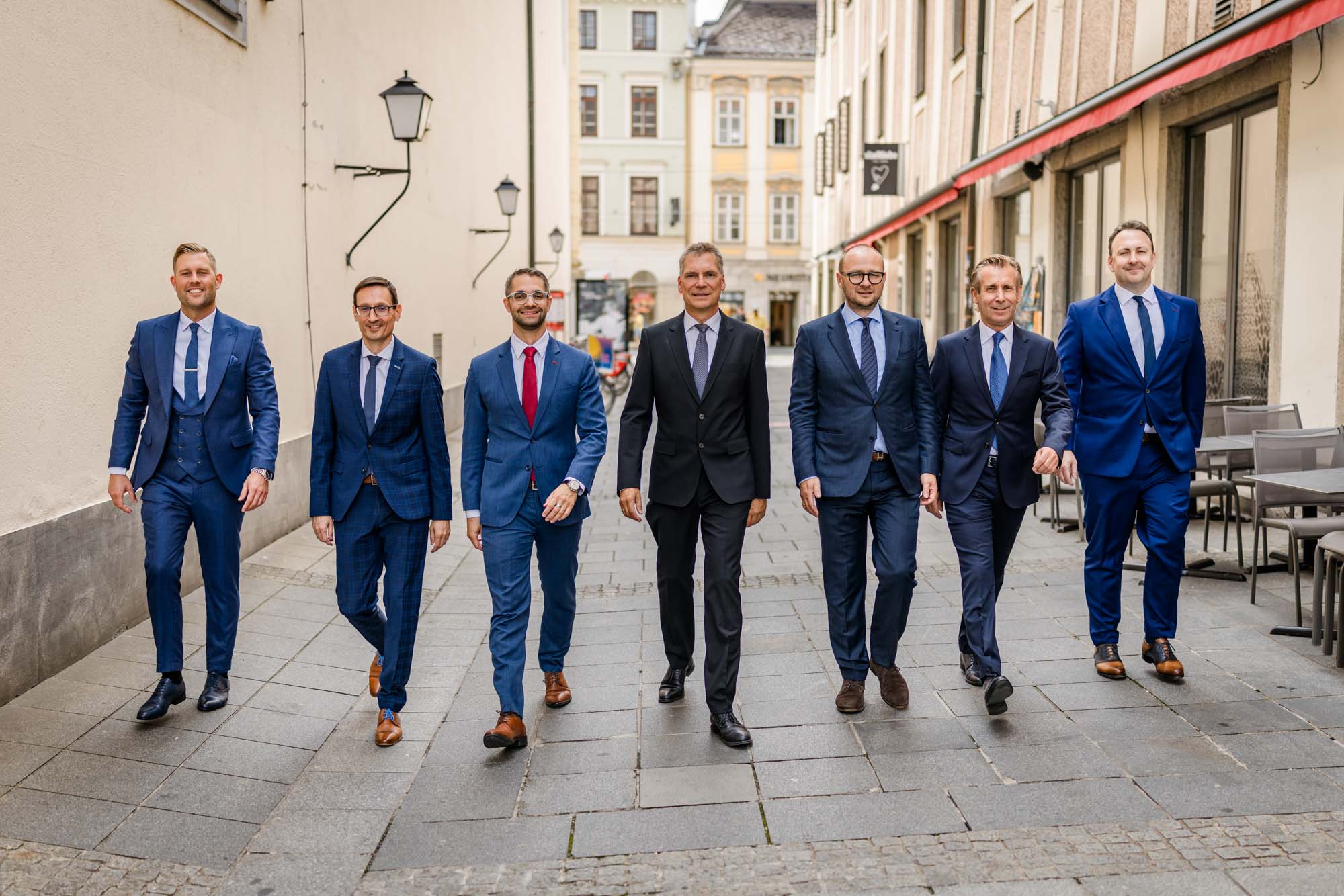 Teamfoto von 7 Rechtsanwälten in Linzer Straße mit älteren Gebäuden im Hintergrund