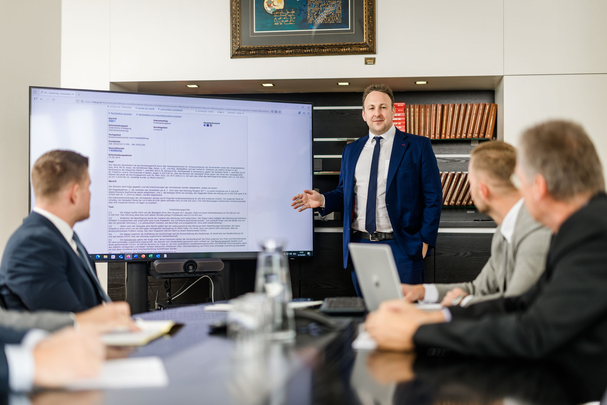 Anwalt präsentiert Inhalte auf einem Bildschirm vor anderen Personen.