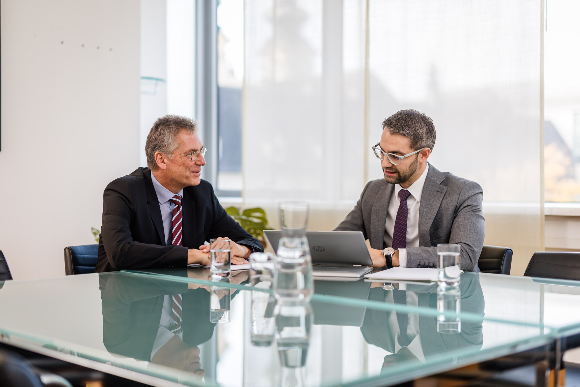Anwalt zeigt Inhalte auf einem Tablet während einer Besprechung und erklärt diesen.