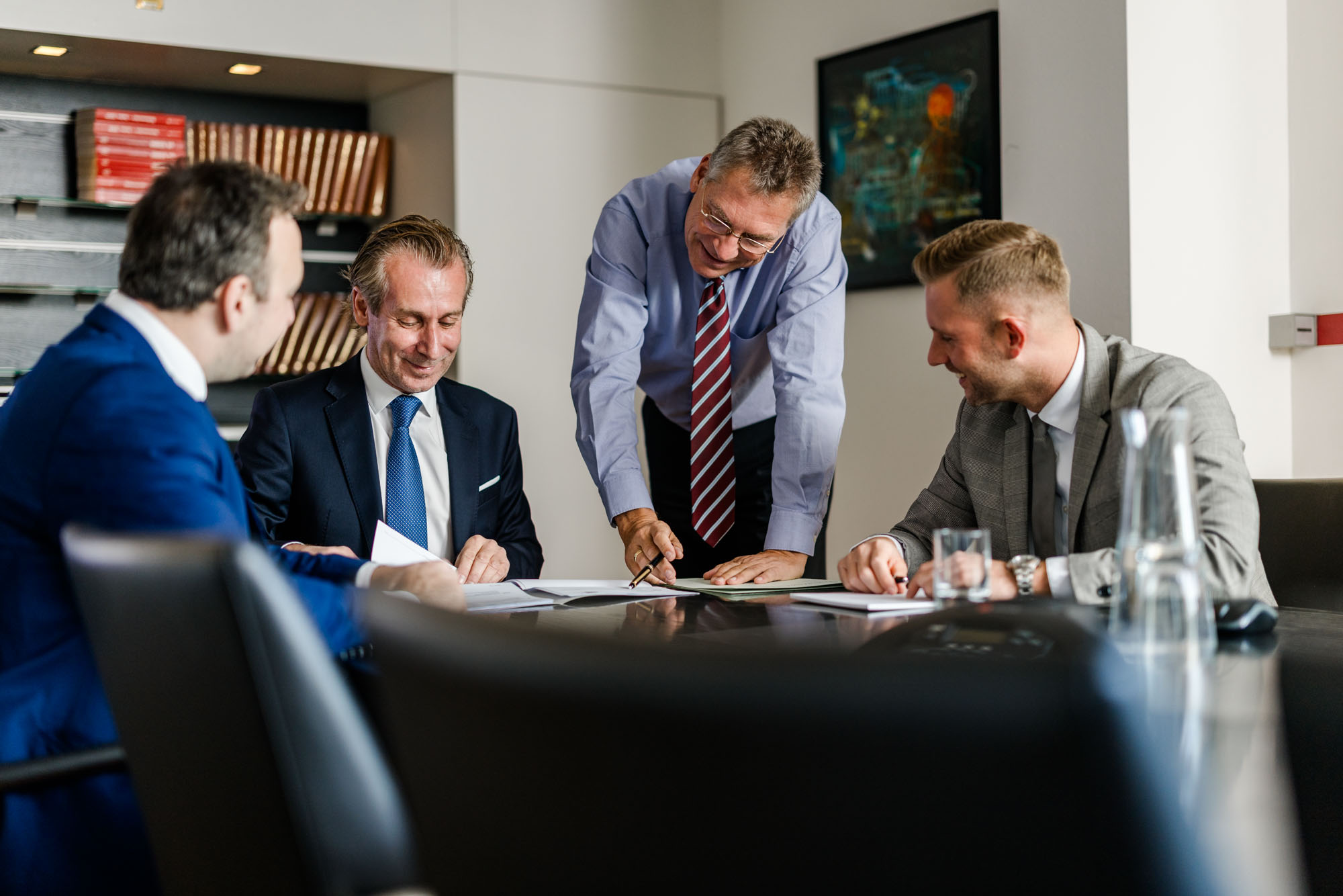 Vier Anwälte arbeiten an einem Tisch gemeinsam an einem Dokument