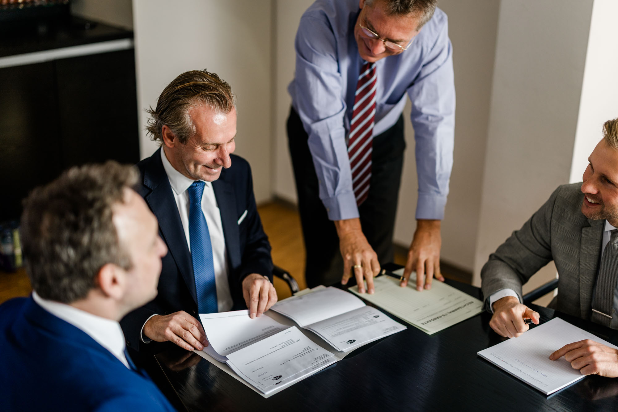 4 Anwälte besprechen Dokumente gemeinsam am Tisch.
