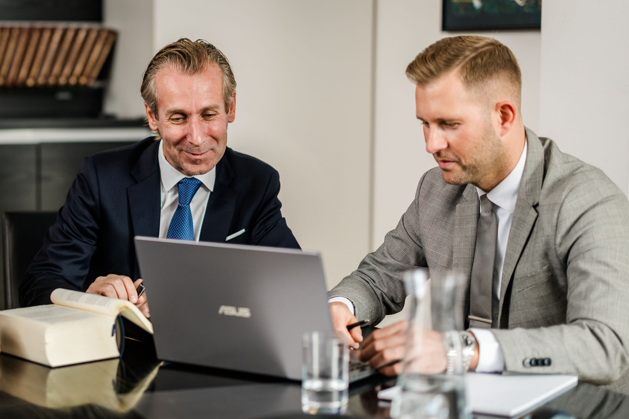 Zwei Männer besprechen etwas am Laptop und sitzen nebeneinander